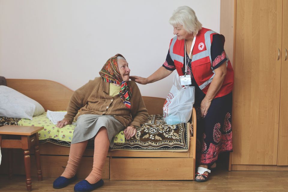 Hilfe des Ukrainischen Roten Kreuzes Mitrbeiterin des DRK streichelt alte Frau